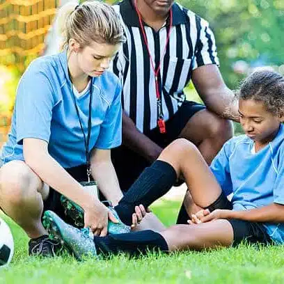 Injured girl soccer player is getting checked by her coach after getting in an accident  