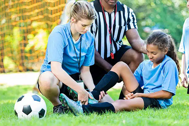 Injured girl soccer player is getting checked by her coach after getting in an accident
