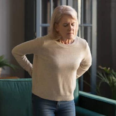 Woman holding her back that suffers from intense pain cause by Lumbar Radiculopathy