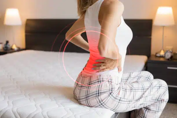female suffering from back pain because of uncomfortable mattress.