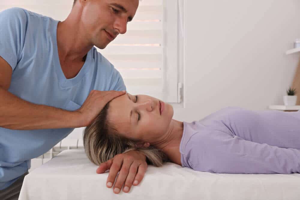 Chiropractor is treating a patient who suffers from auto accident by having a neck adjustment.
