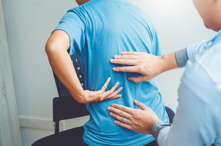 Chiropractor having an evaluation with a male patient who suffers from back pain.