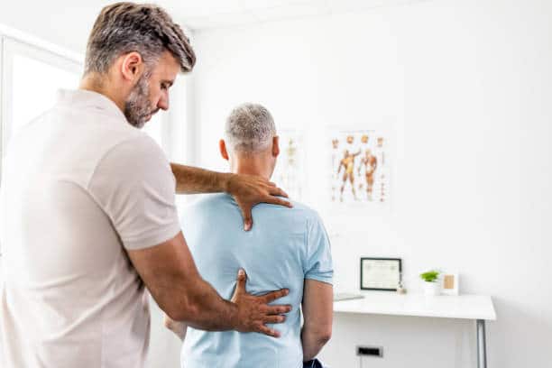 Chiropractor having an evaluation with a male patient who suffers from back pain.