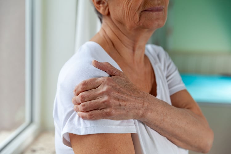 Senior woman suffers from intense shoulder pain.