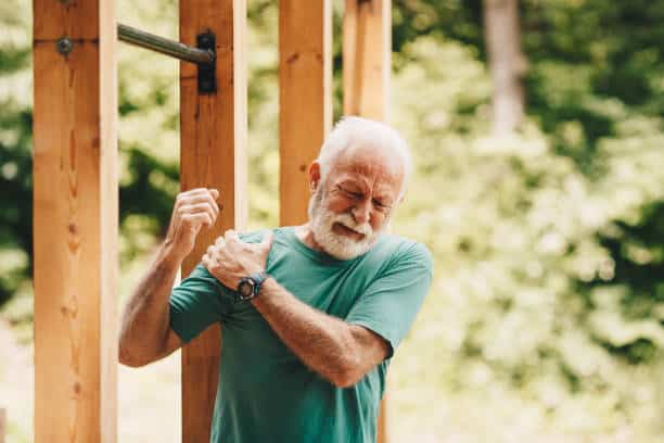 Senior man suffering from shoulder pain caused by Arthritis while working out.
