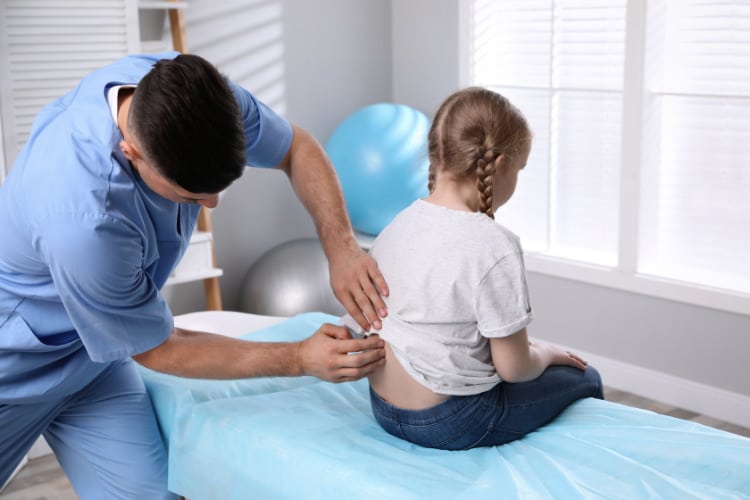 pediatric chiropractor doing some back adjustment to a young patient.