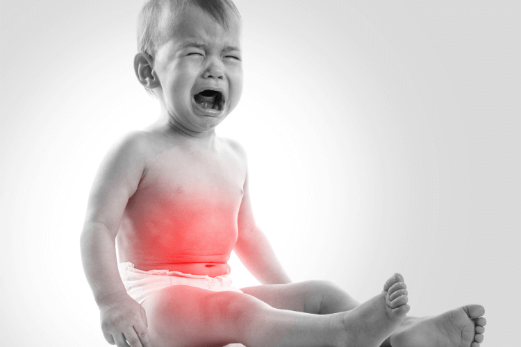 Young baby boy cries feeling uncomfortable suffering from Digestive Issues.