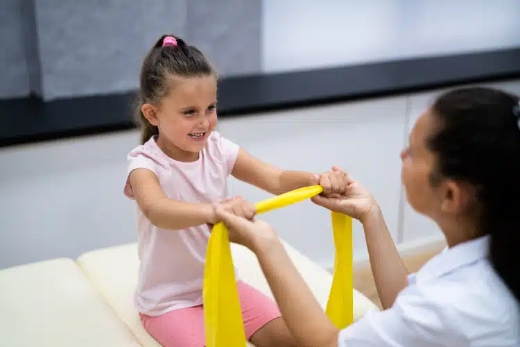 Pediatric chiropractor doing stretching exercises with her young patient.