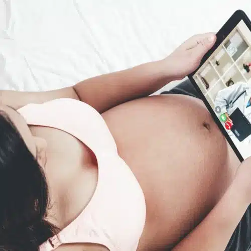 Pregnant woman watching reviews from a certain prenatal care online | prenatal chiropractic care in columbus