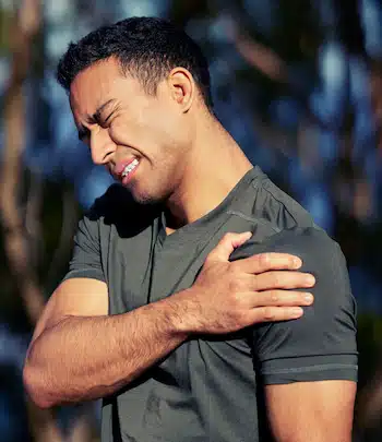 Shot of a sporty young man holding his shoulder in pain while exercising outdoors