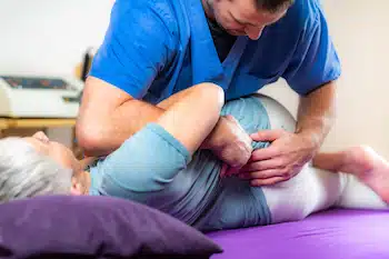 chiropractor doing hip alignment to a patient at rehab
