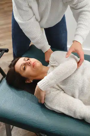 osteopath working with female patient shoulder