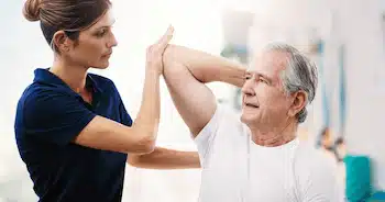 experienced chiropractor moving elderly man's elbow to check on his injury for patient-centered care | elbow pain treatment in columbus ne