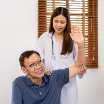 female physical therapist conducting Comprehensive Assessment on middle aged man patient as initial procedure of Fibromyalgia Treatment