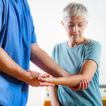 senior woman being assessed by therapist for joint pain before treatment
