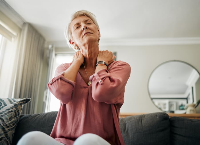 An old woman who is stretching her neck due to neck pain 