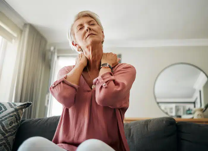 An old woman who is stretching her neck due to neck pain 
