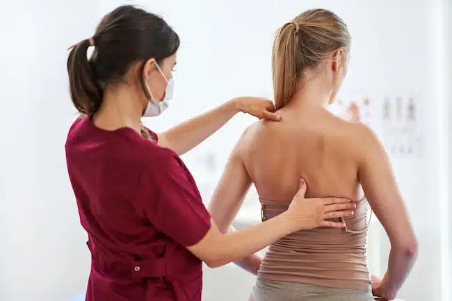 therapist doing assessment on patient's back who has scoliosis