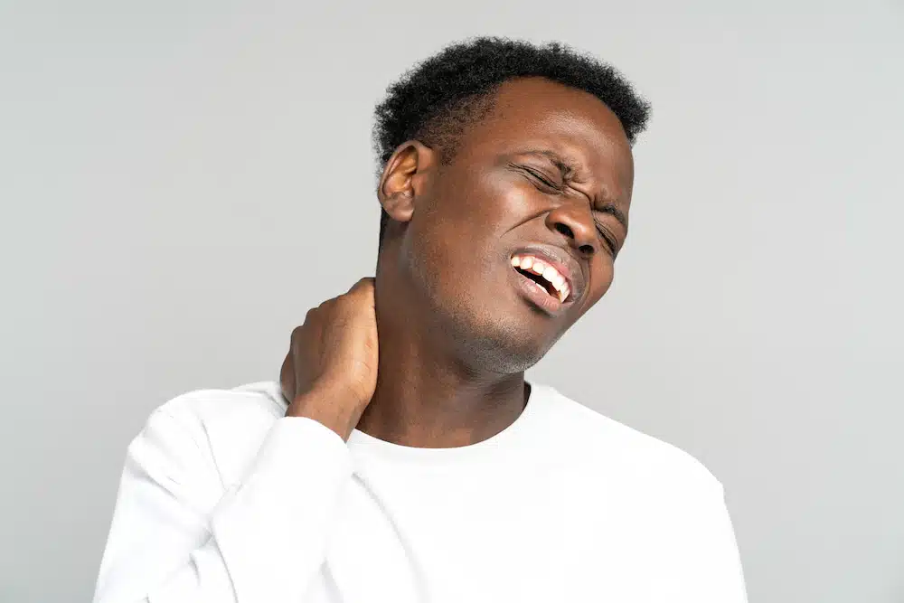 man with pinched nerve on the neck holding his neck while in pain