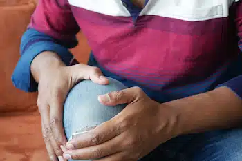 man with Osteoarthritis holding his knee from pain