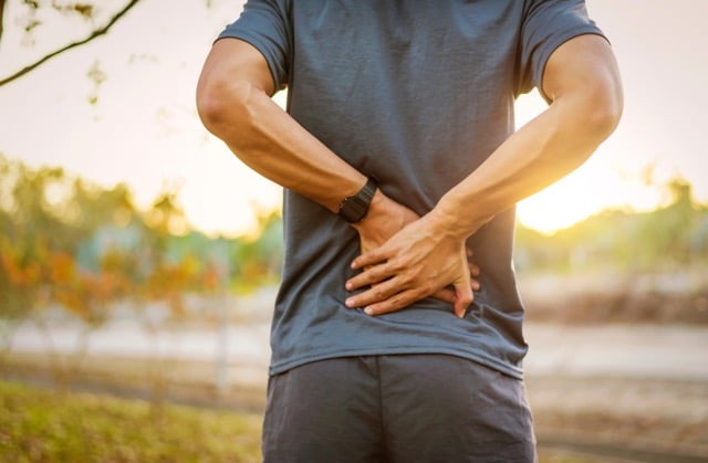 Back pain, close up young man has muscle injury during outdoor exercise