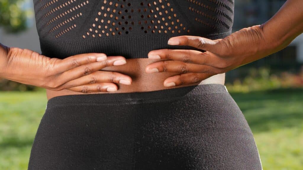 Woman holding her lower back, showing symptoms of sciatica pain.
